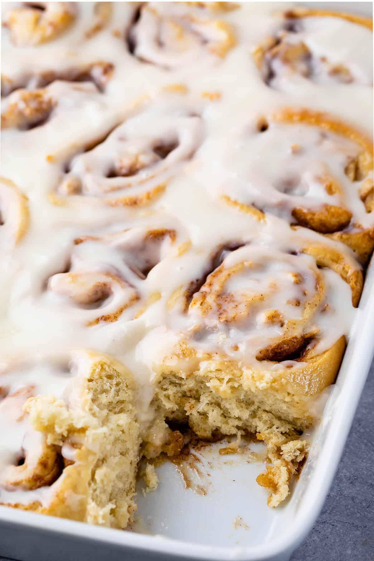 white pan of cinnamon rolls with one taken out