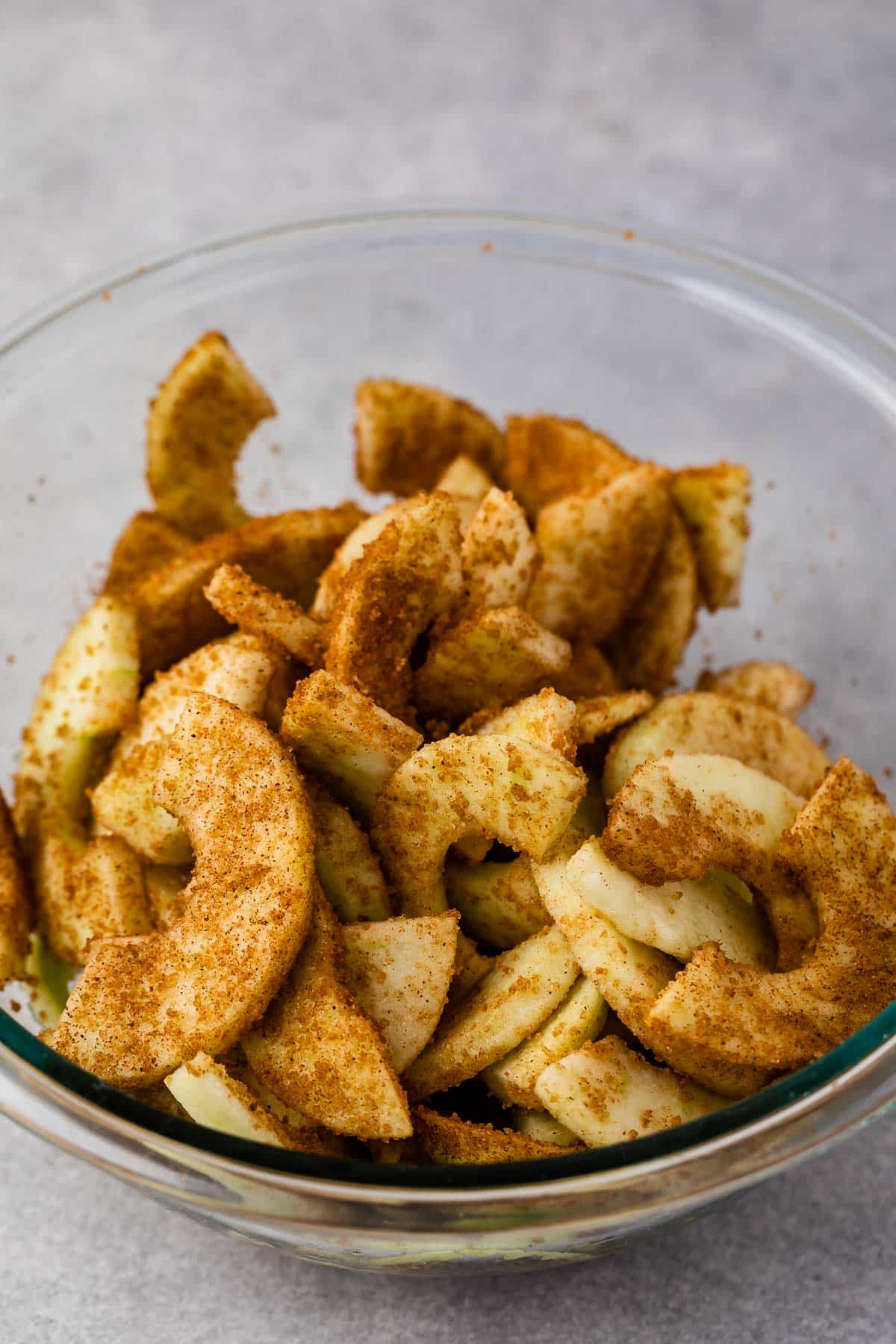 apples cut and covered in cinnamon in a clear bowl