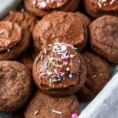 multiple chocolate cookies in a pan with some frosted with sprinkles on top