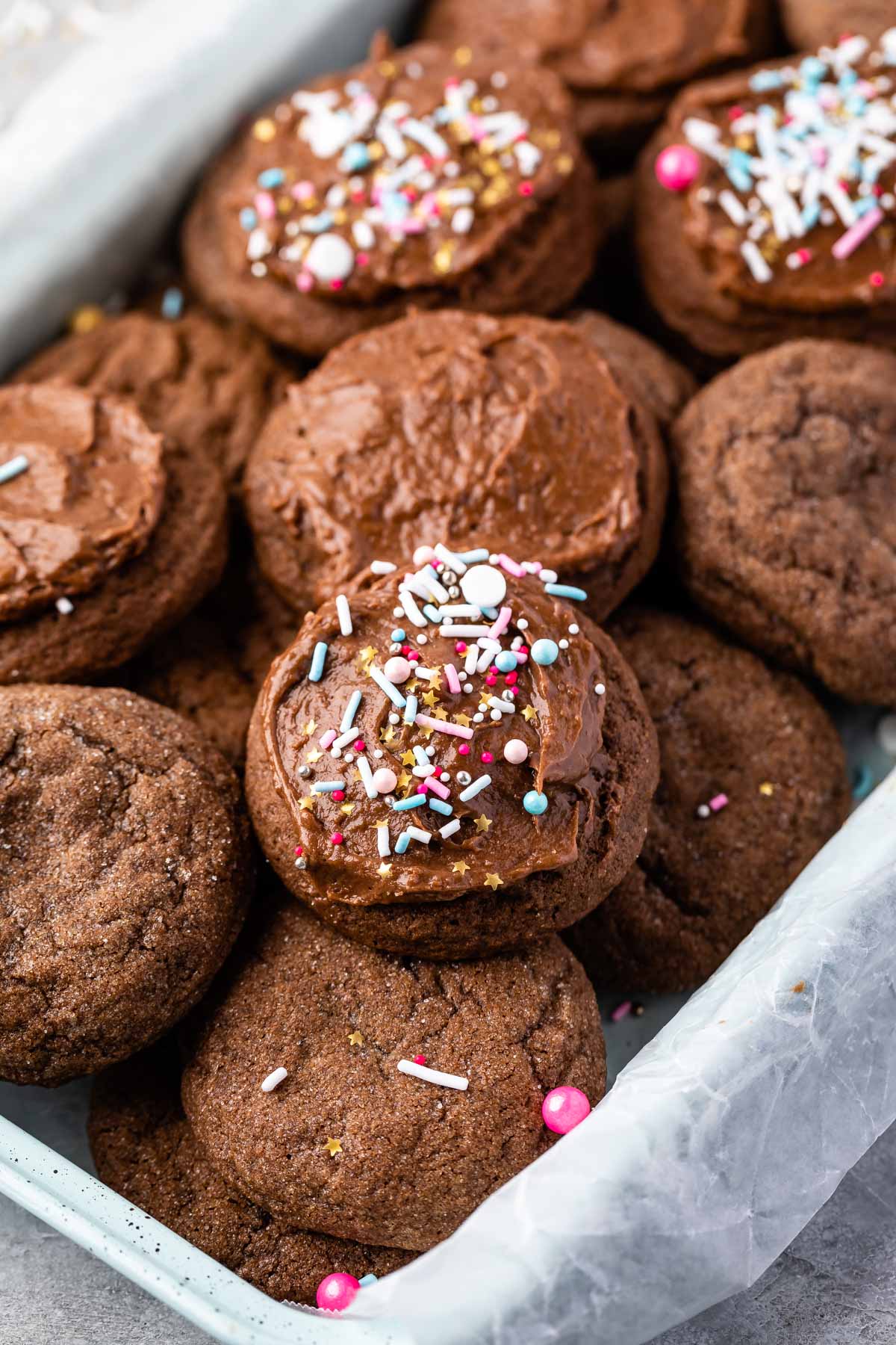 multiple chocolate cookies in a pan with some frosted with sprinkles on top