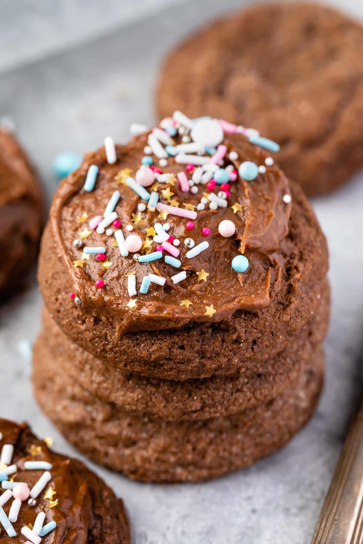 stacked chocolate cookies with the one on top frosted with colorful sprinkles