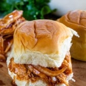 chicken and onions between a roll of bread on a cutting board