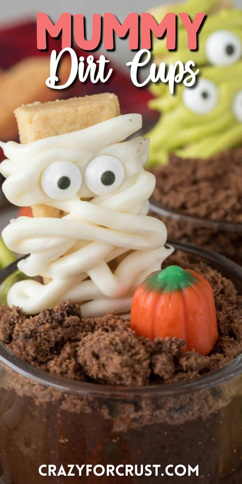 mummy decorated cookie in a dirt cup next to a candy corn pumpkin with words on the photo