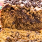 close up photo of loaf of pumpkin quick bread with chocolate chips, one slice laying on cutting board with words on photo.