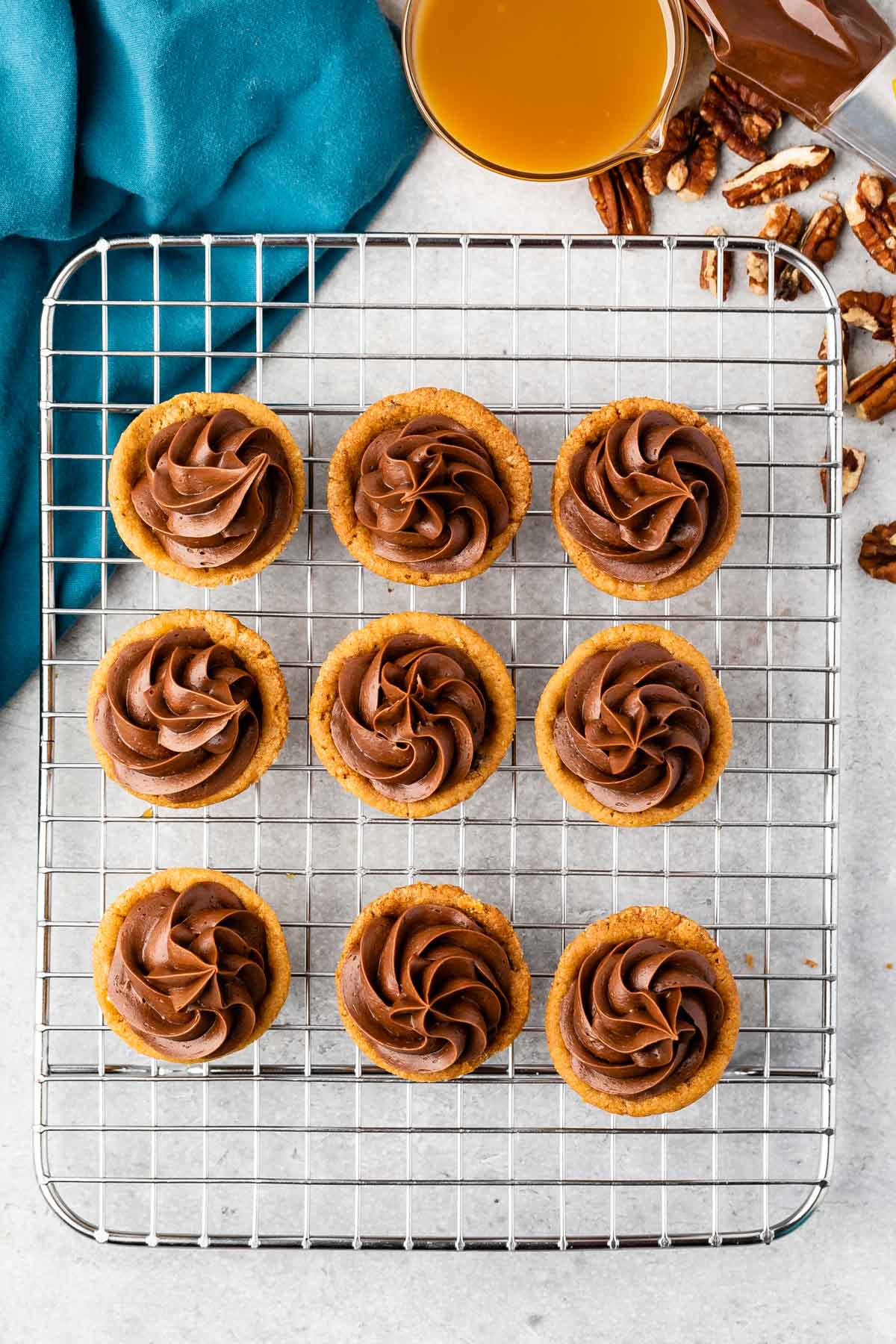 multiple turtle cups with chocolate frosting on top laying on a drying rack