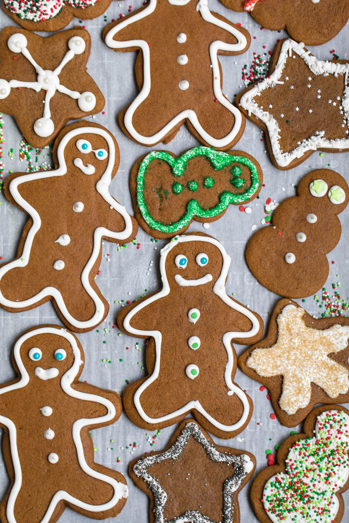 parchment paper with gingerbread men and snowmen on it outlined with royal icing and sprinkles