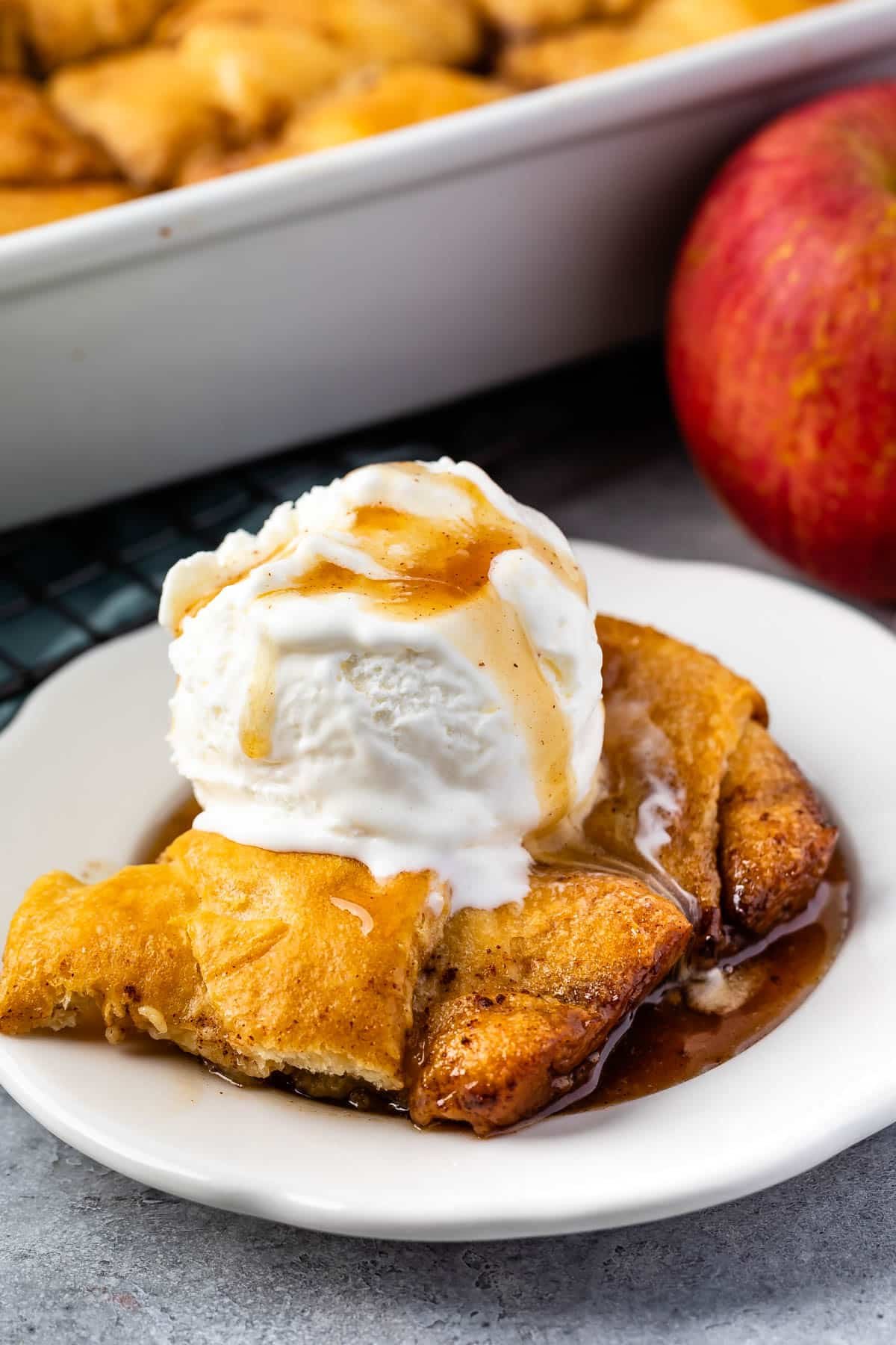 apple dumpling in a white plate with vanilla ice cream on top