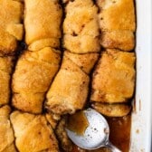 multiple dumplings laid in a pan with a silver spoon around