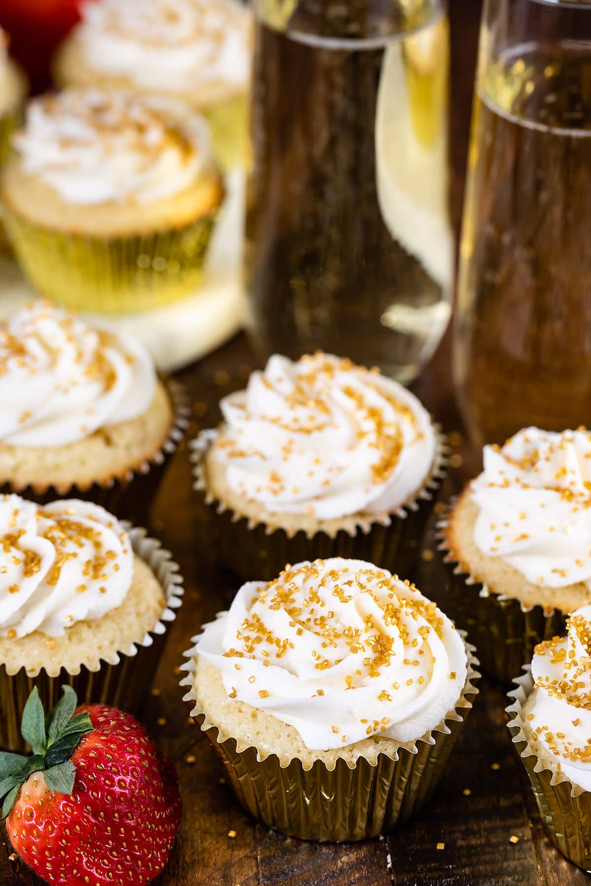 cupcakes in a gold tin with white frosting and gold sprinkles on top