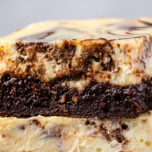 stacked square slices of brownies with a layer of cheesecake on top with words on the image