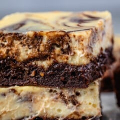 stacked square slices of brownies with a layer of cheesecake on top