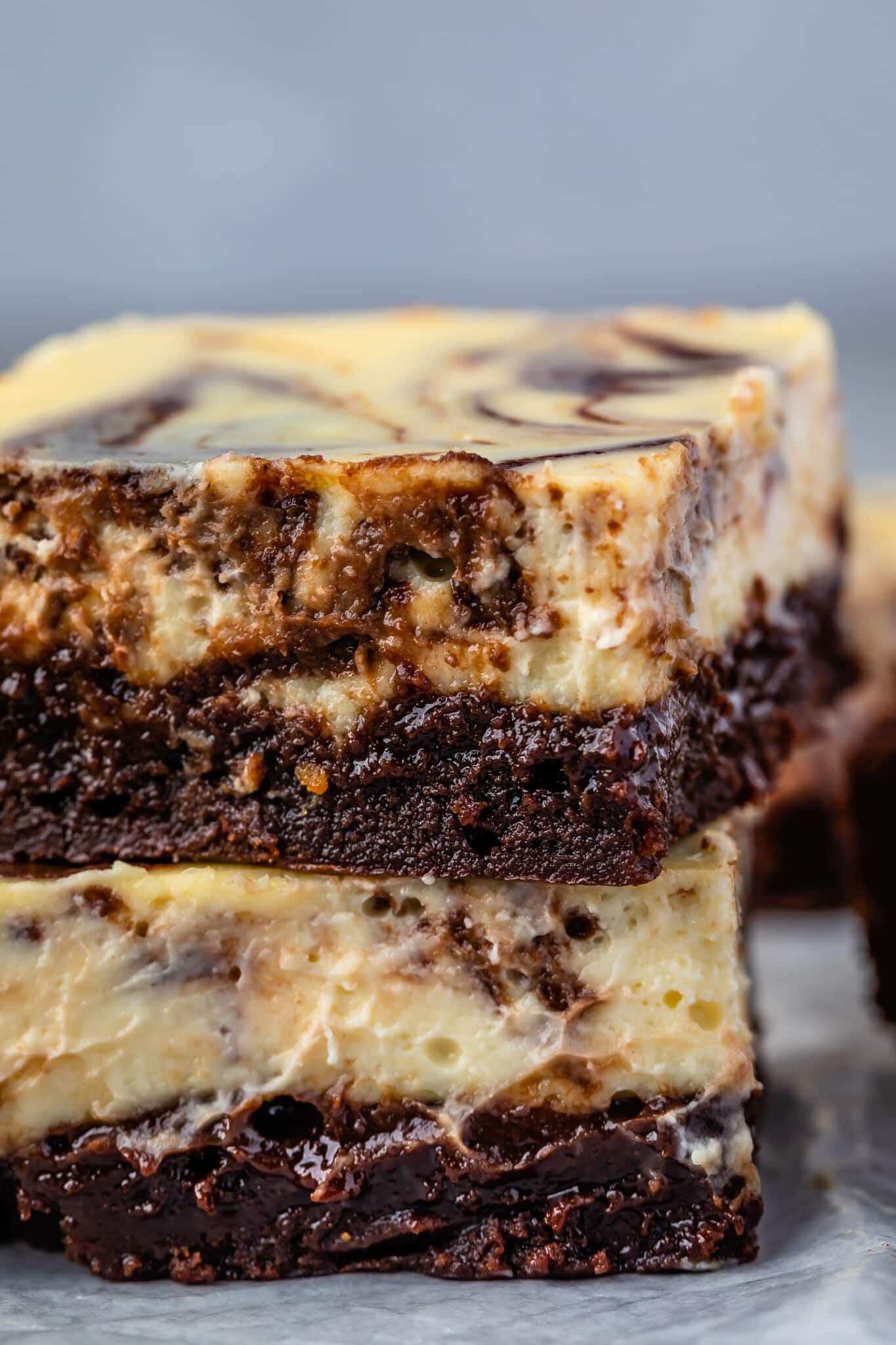 stacked square slices of brownies with a layer of cheesecake on top