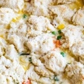 chicken and biscuits cooked together in a white pan with words on top