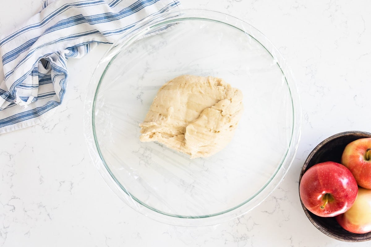 dough in bowl with plastic wrap.