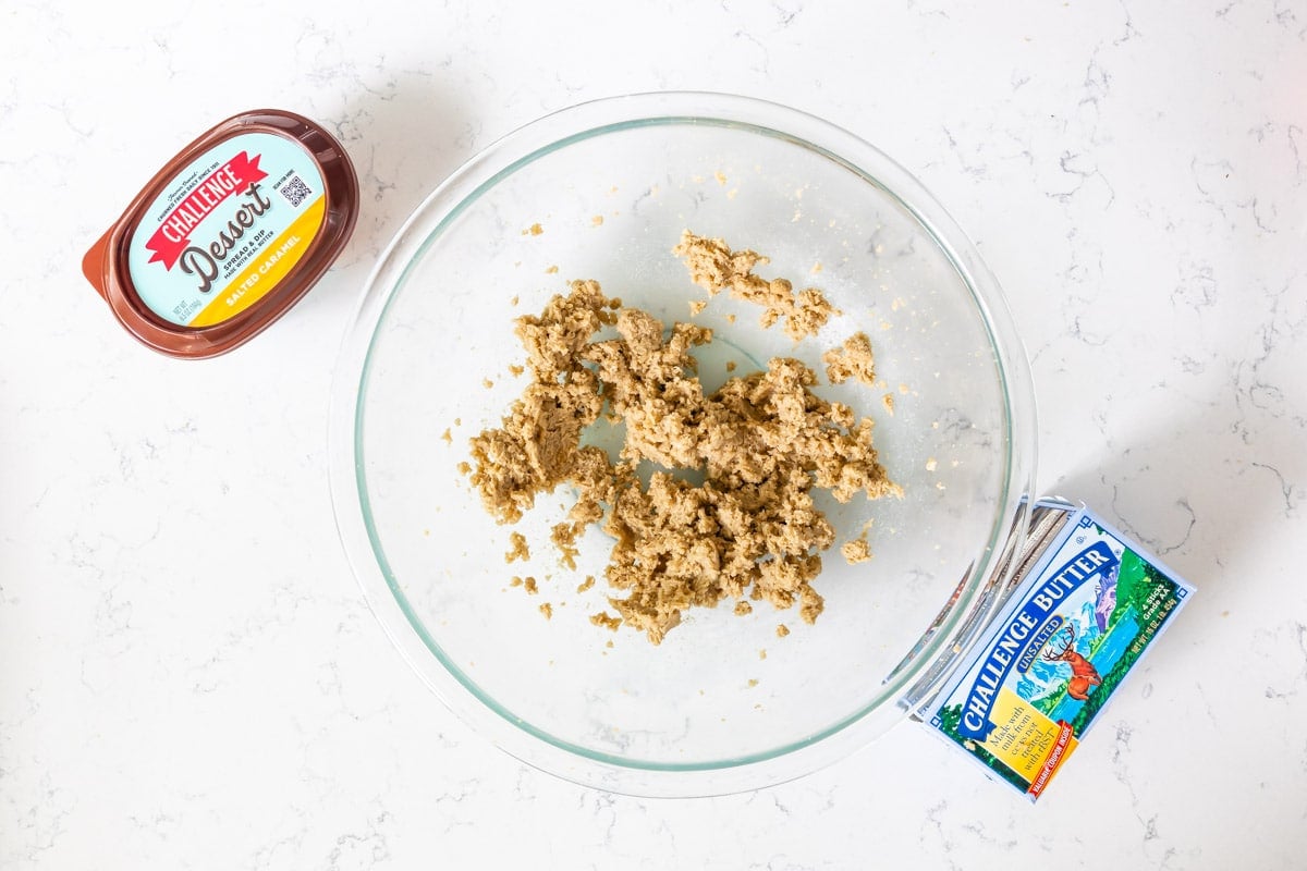 creamed butter and brown sugar in glass bowl on counter with butter and dessert spread.