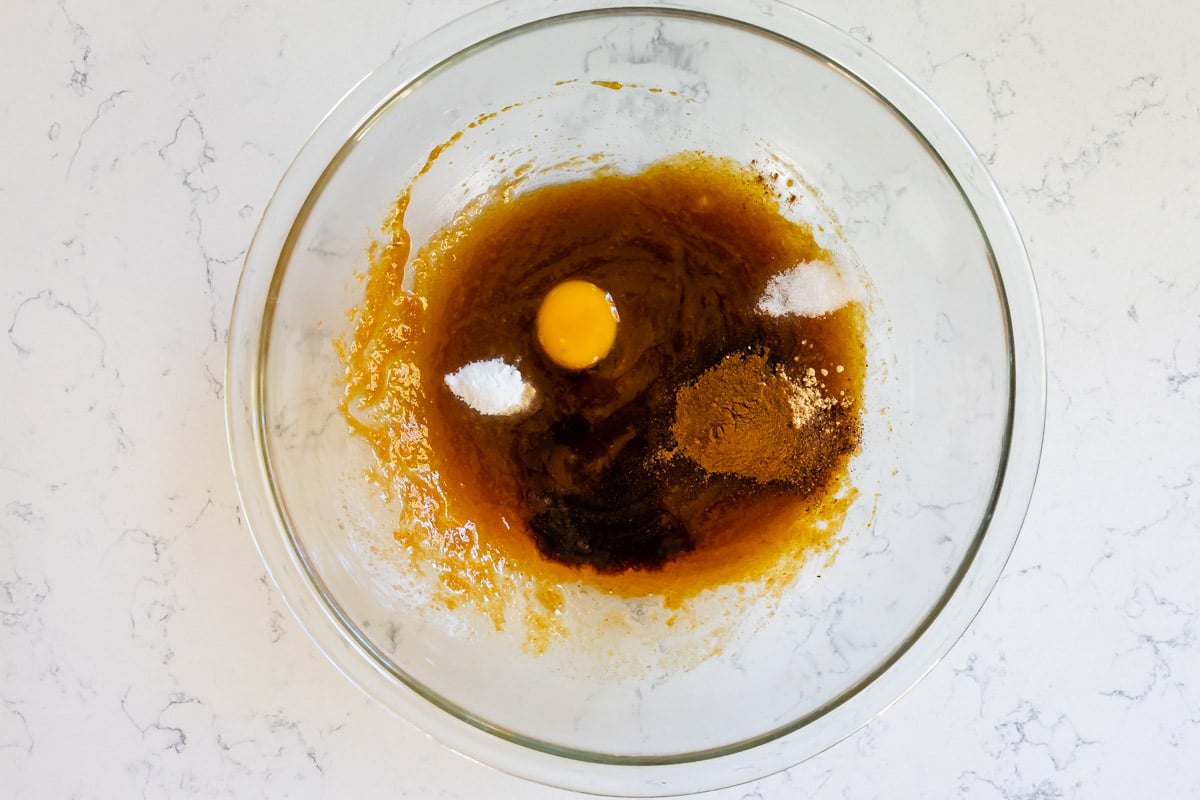 clear glass bowl with pumpkin mixture egg yolk, spices, salt, and baking soda.