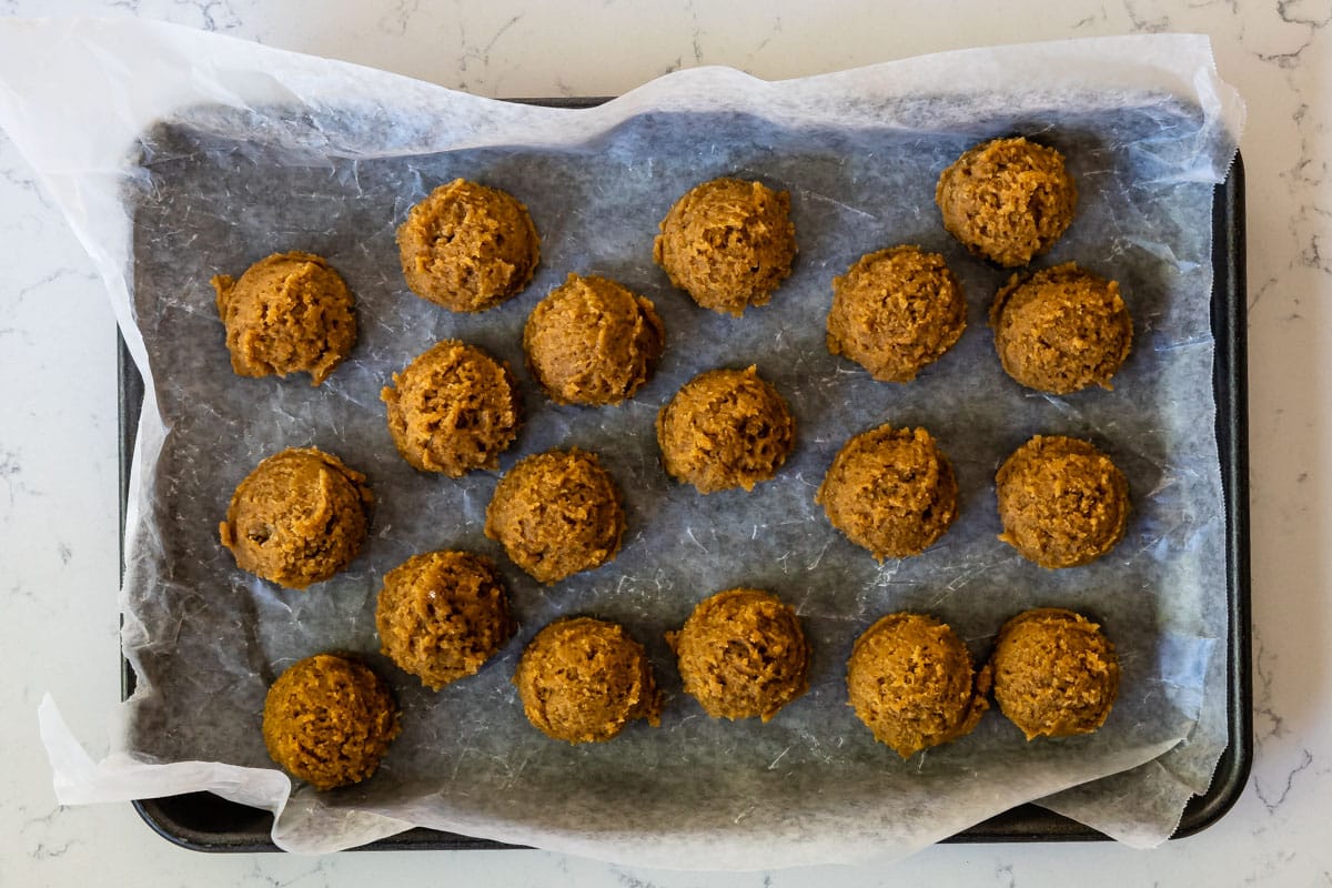 cookie dough balls on cookie sheet lined with parchment.