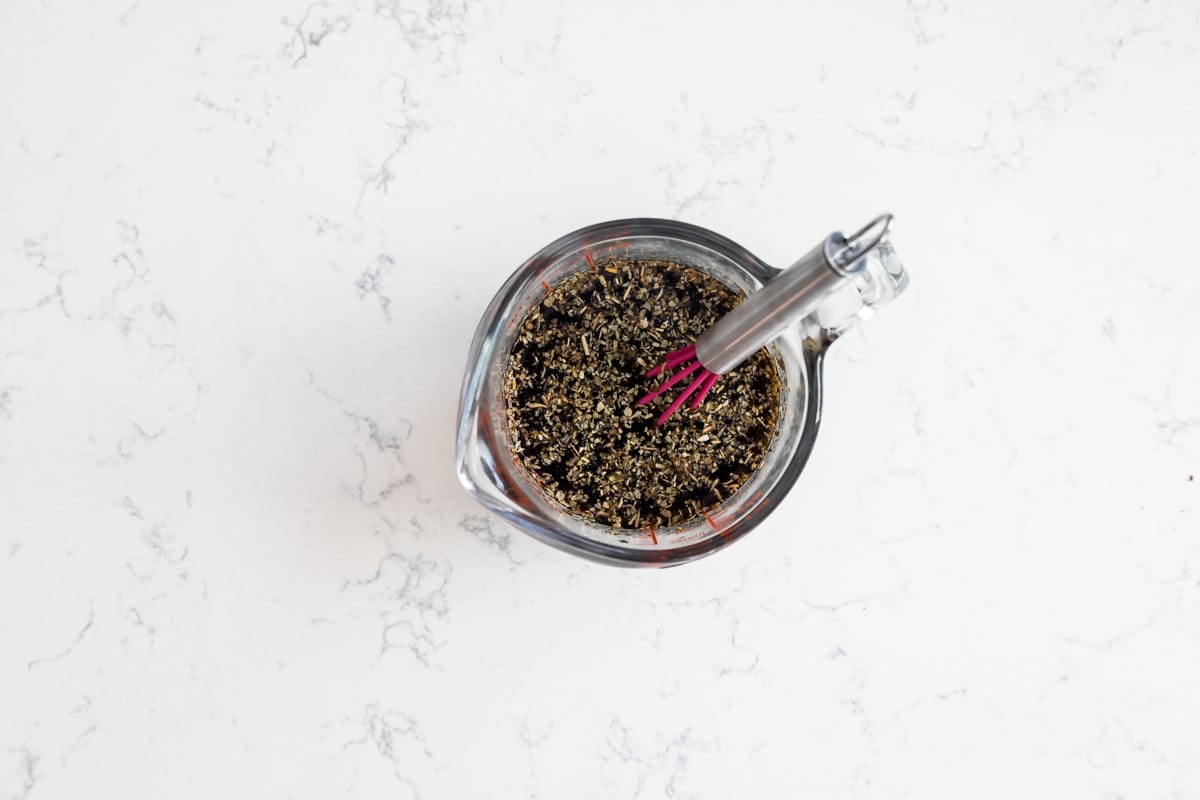 soy sauce in a measuring cup being stirred with a whisk