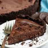 one slice of chocolate pie on a white plate next to a gold fork