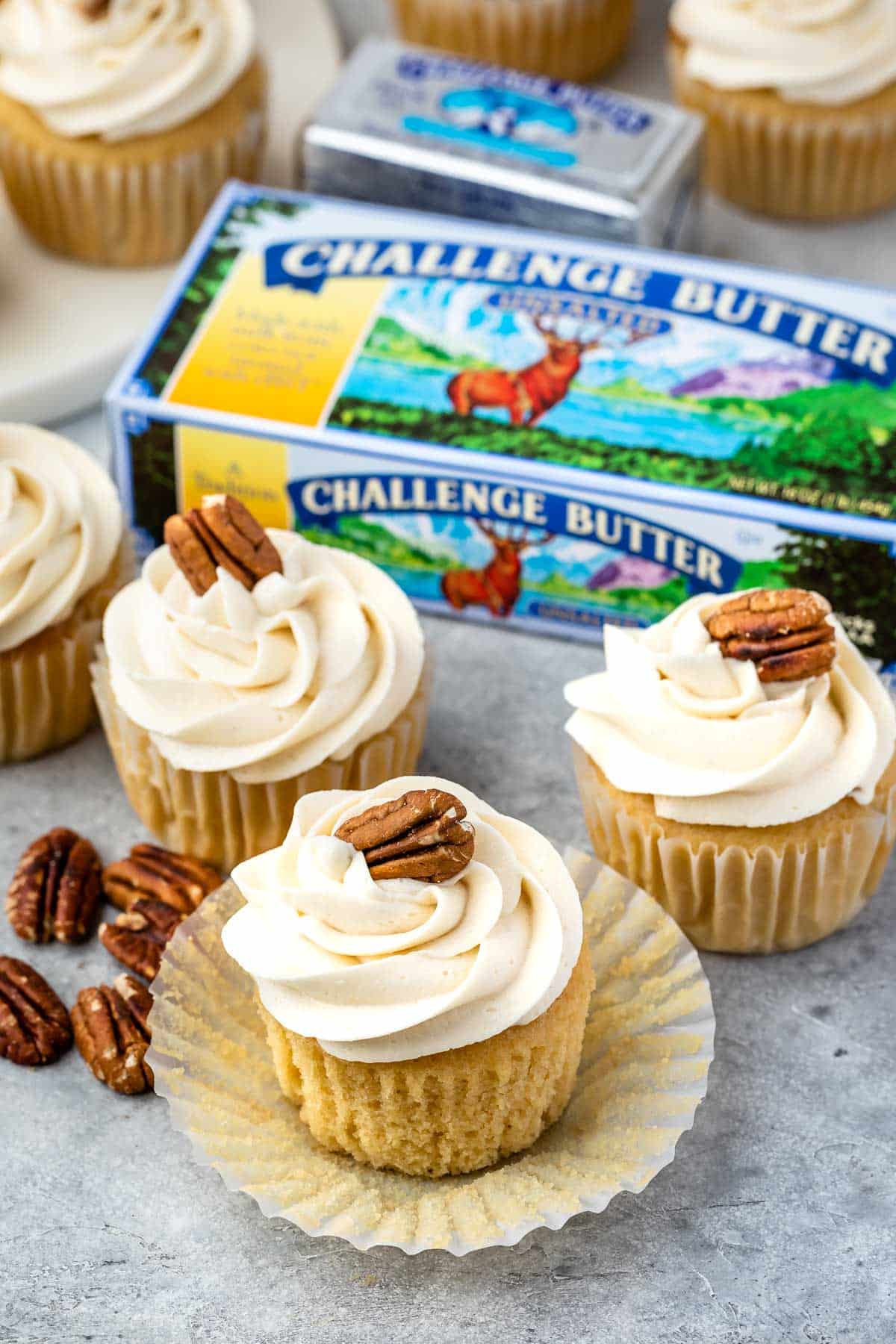 three pecan cupcakes with white frosting and a pecan on top