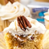 pecan pie cupcakes cut in half with white frosting and a pecan on top