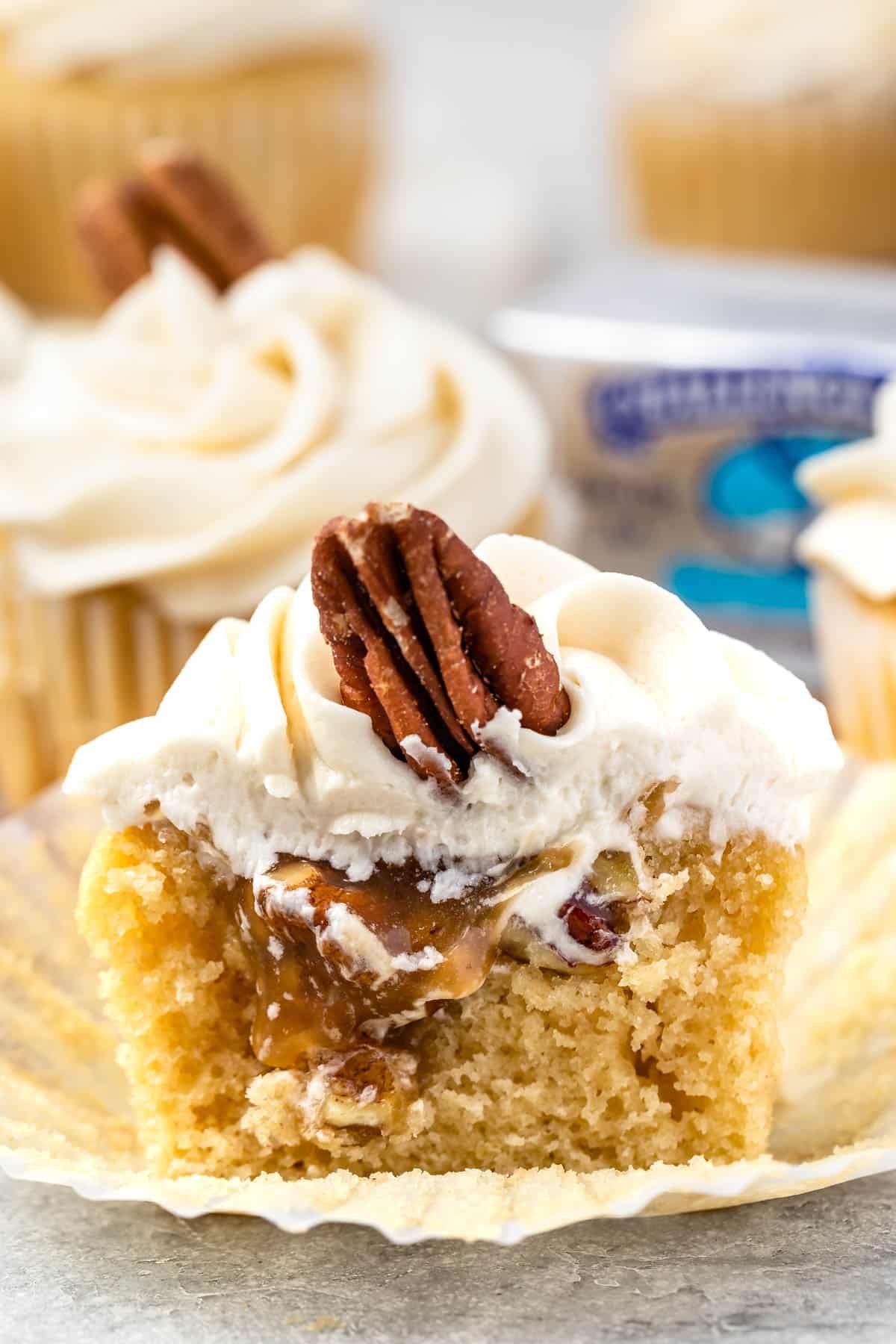 pecan pie cupcakes cut in half with white frosting and a pecan on top