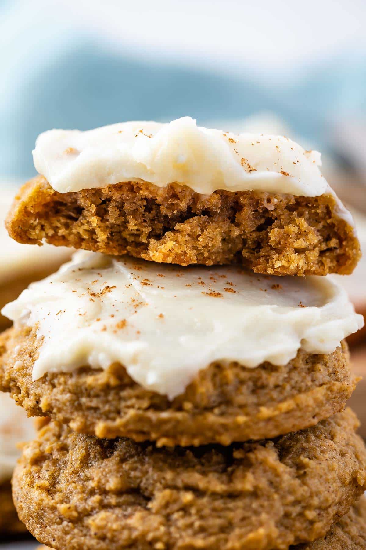 stacked pumpkin cookies with frosting on top and the cookie on top cut in half