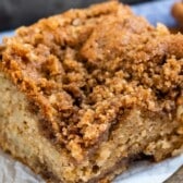 crumb cake on a white towel next to a silver fork with words on top