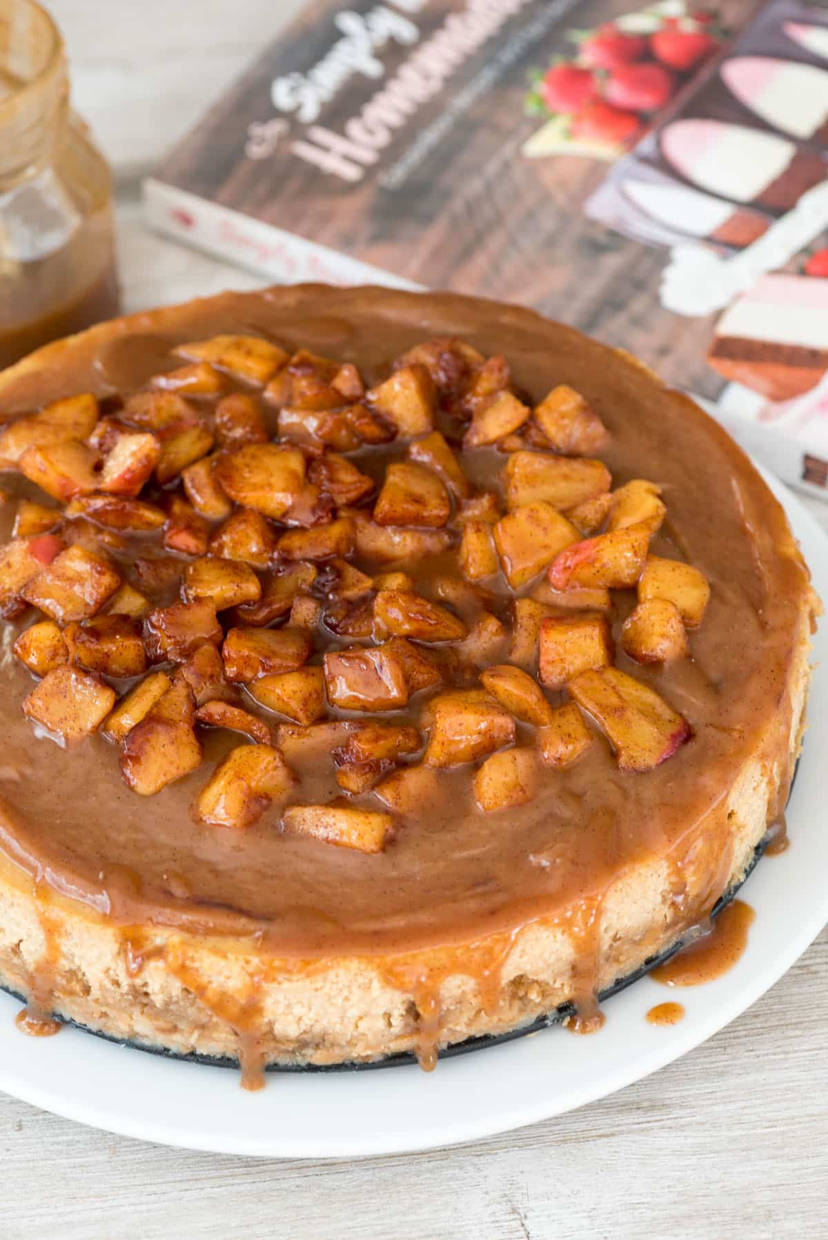 full cheesecake with apples baked on top on a white plate