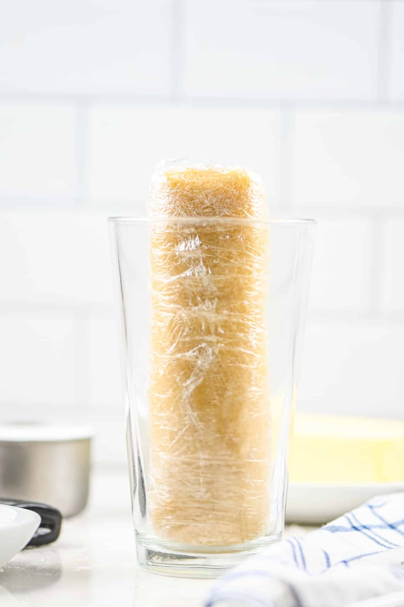 cookie dough log wrapped in plastic in a glass