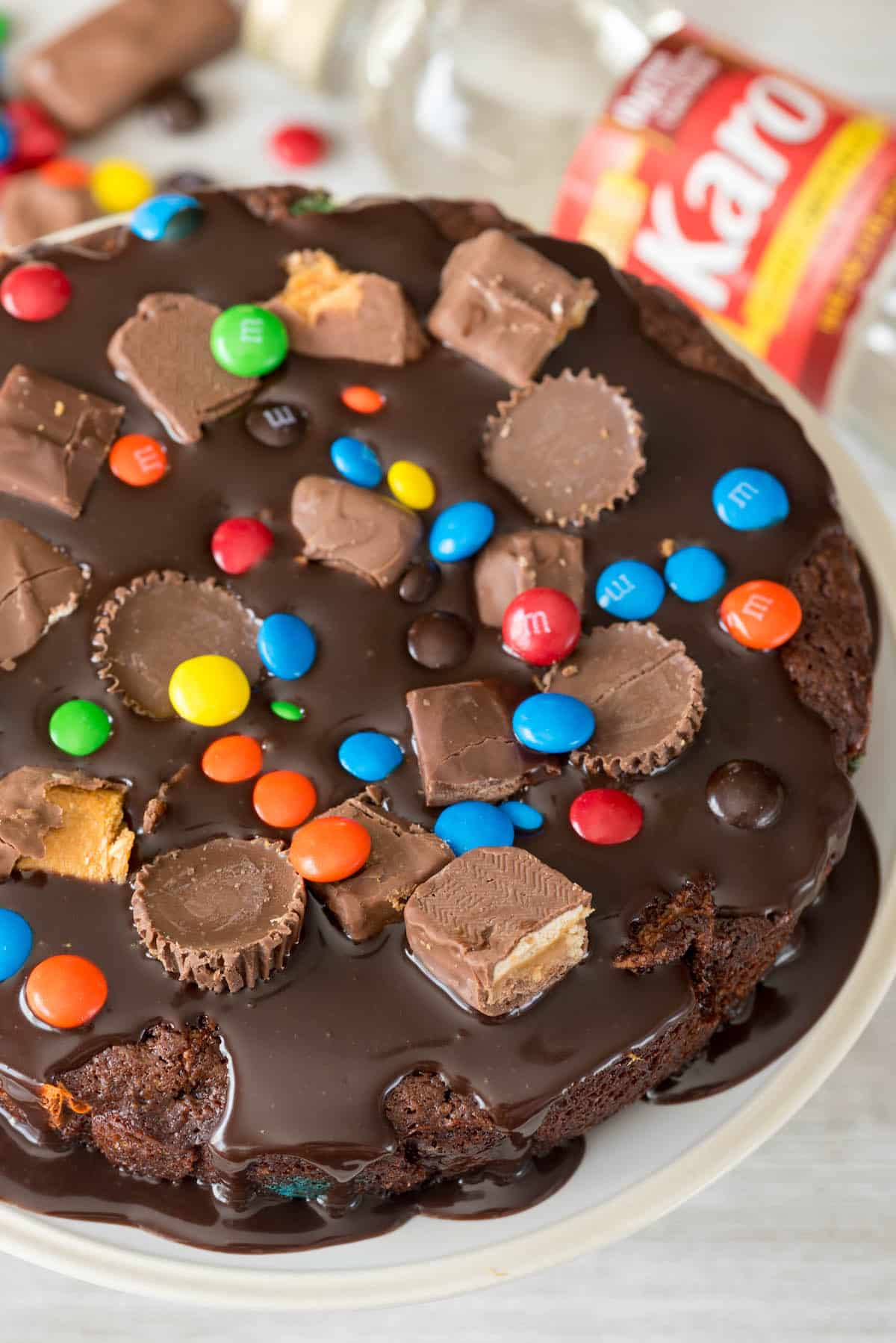 cake with m&ms and peanut butter cups baked in on top sitting on a white platter
