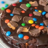 cake with m&ms and peanut butter cups baked in on top sitting on a white platter