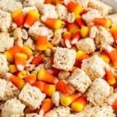 A bowl filled with rice crispy treat squares, candy corn, and peanuts, creating a colorful and festive Halloween Snack Mix.