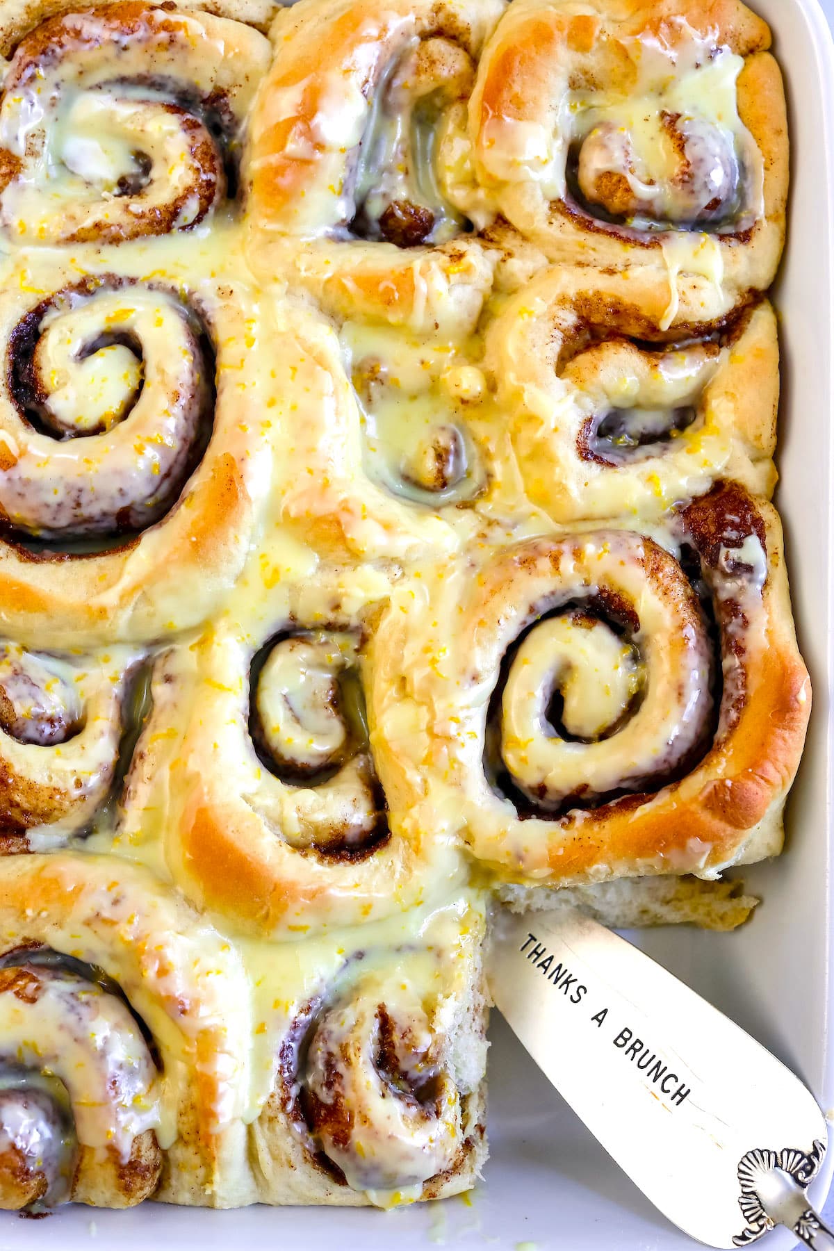 sweet rolls in a white pan baked together with frosting poured on top