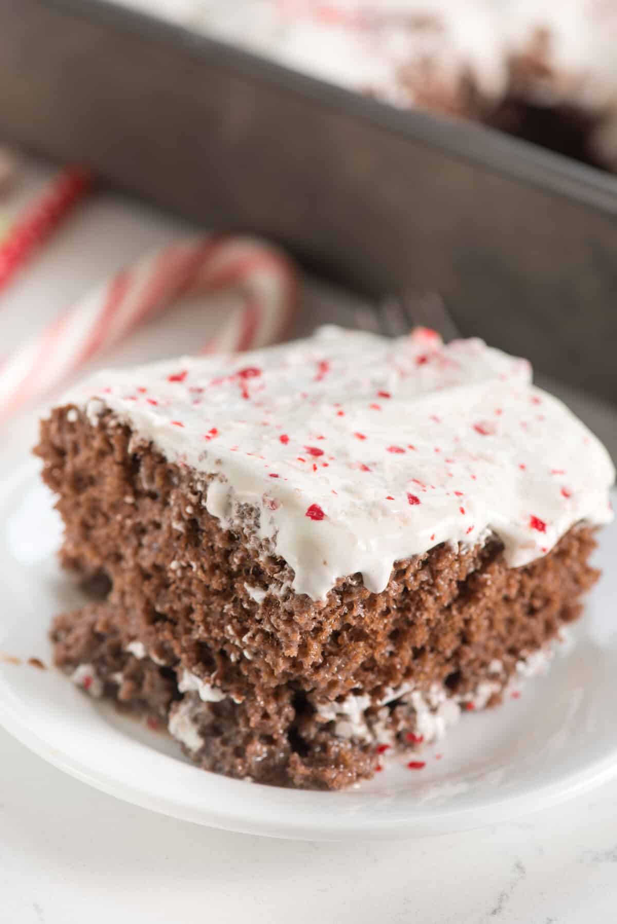 cake with white frosting and crushed peppermint on top on a white plate