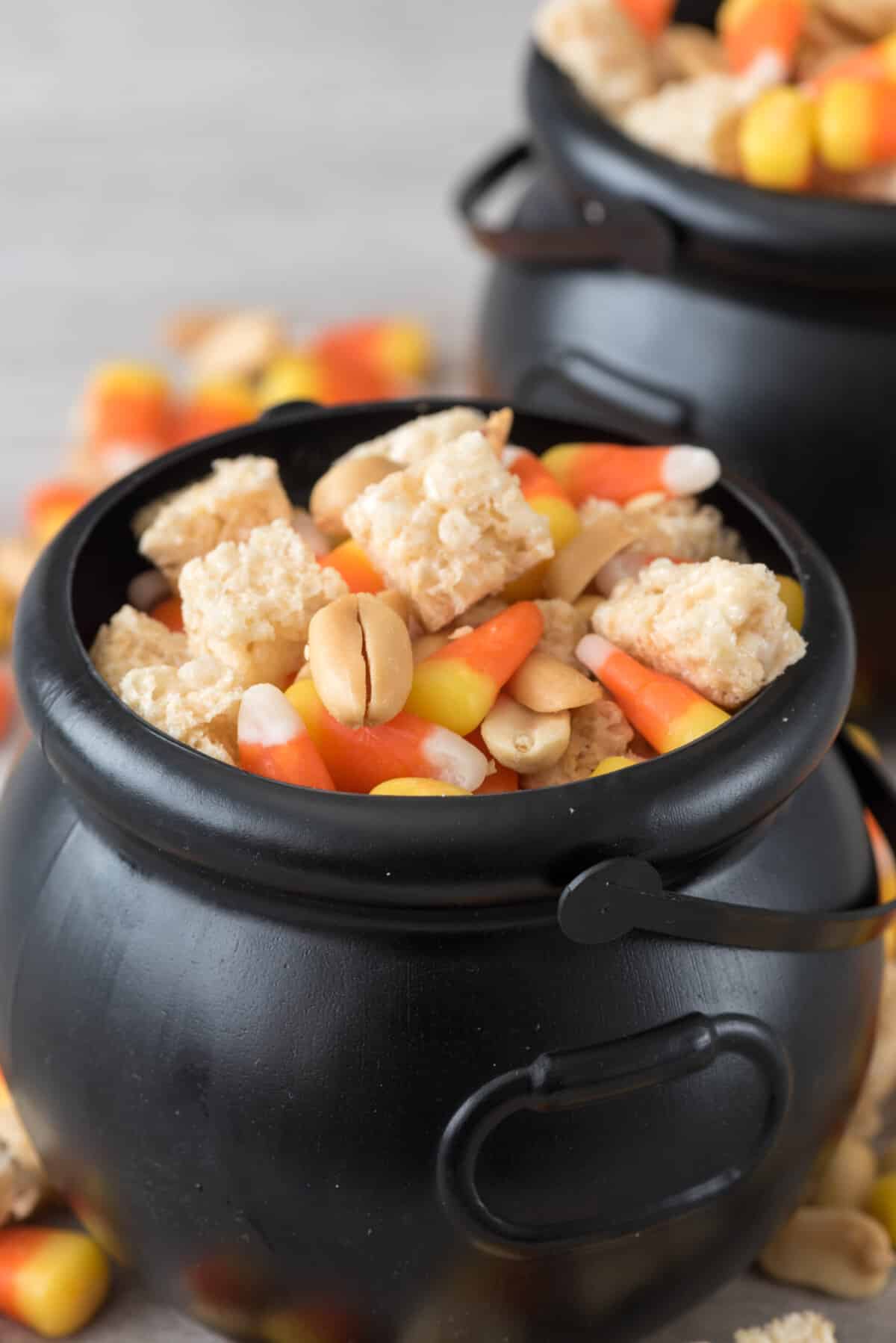 Krispie Treats and candy corn and nuts mixed together in a black cauldron