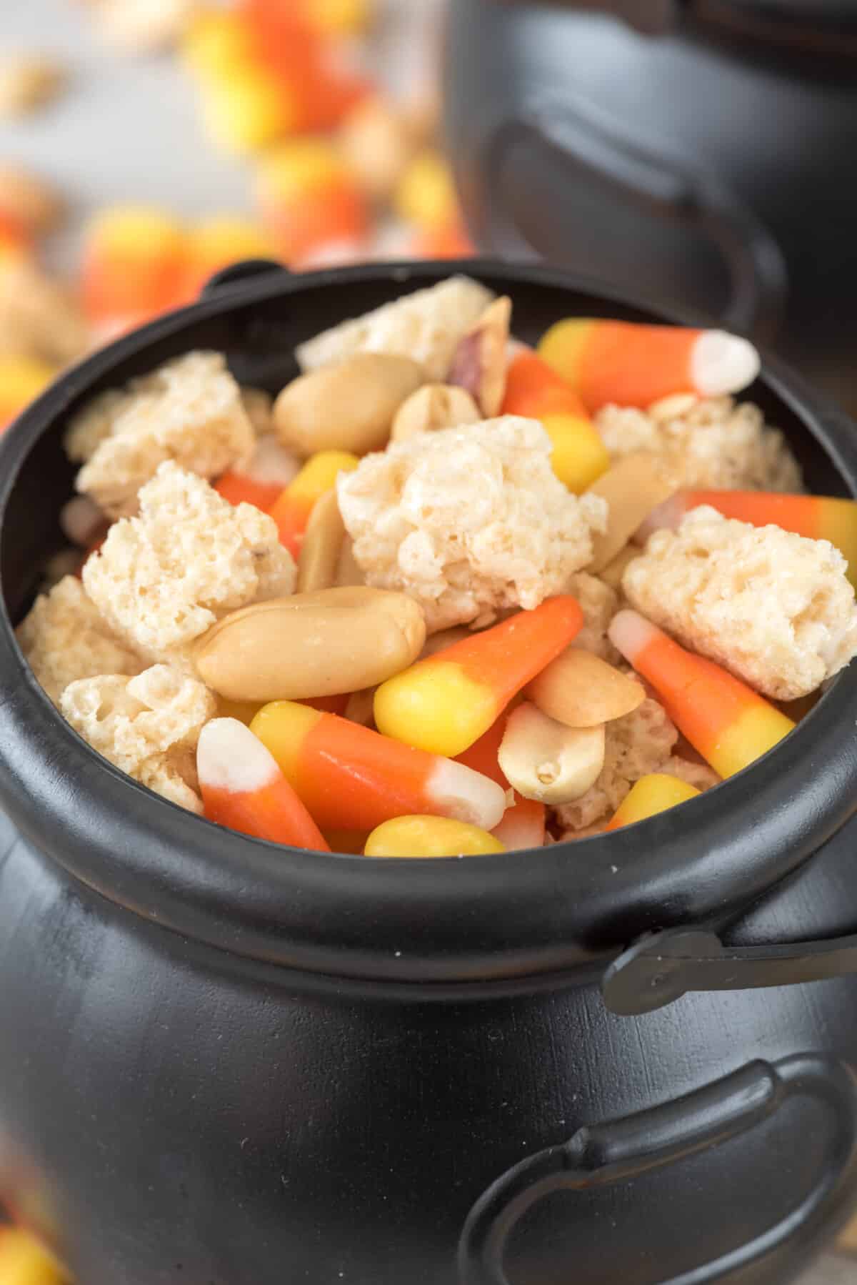 Krispie Treats and candy corn and nuts mixed together in a black cauldron