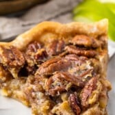 one slice of pecan pie on a white plate with sliced apples in the back with words on top