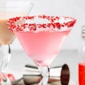 candy cane martini in a martini glass with crushed candy canes on the rim with words on top