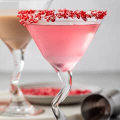 candy cane martini in a martini glass with crushed candy canes on the rim