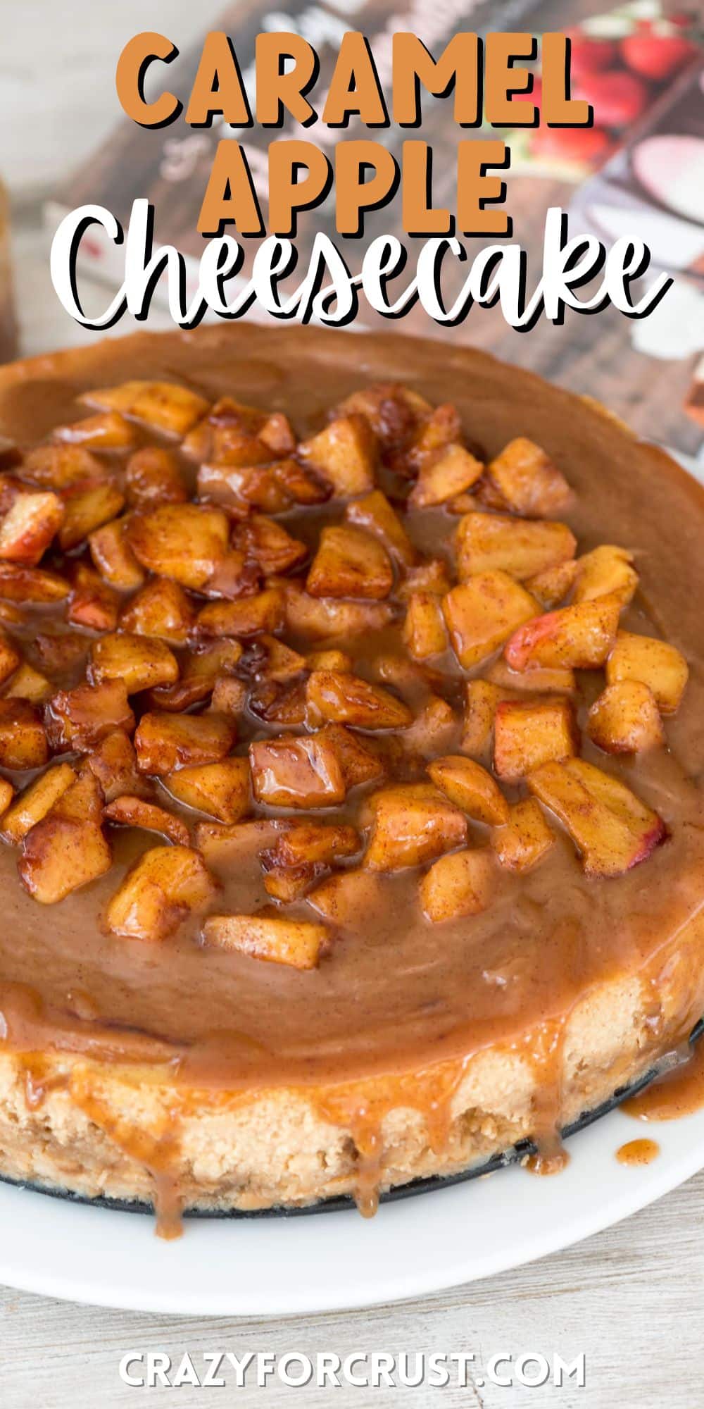 full cheesecake with apples baked on top on a white plate with words on top