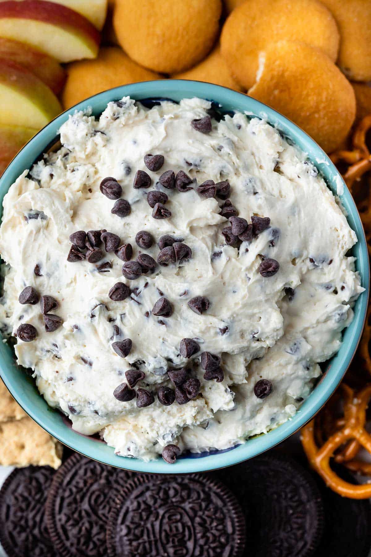 cookie dough in a dark blue bowl surrounded by cookies