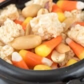 Krispie Treats and candy corn and nuts mixed together in a black cauldron with words on top