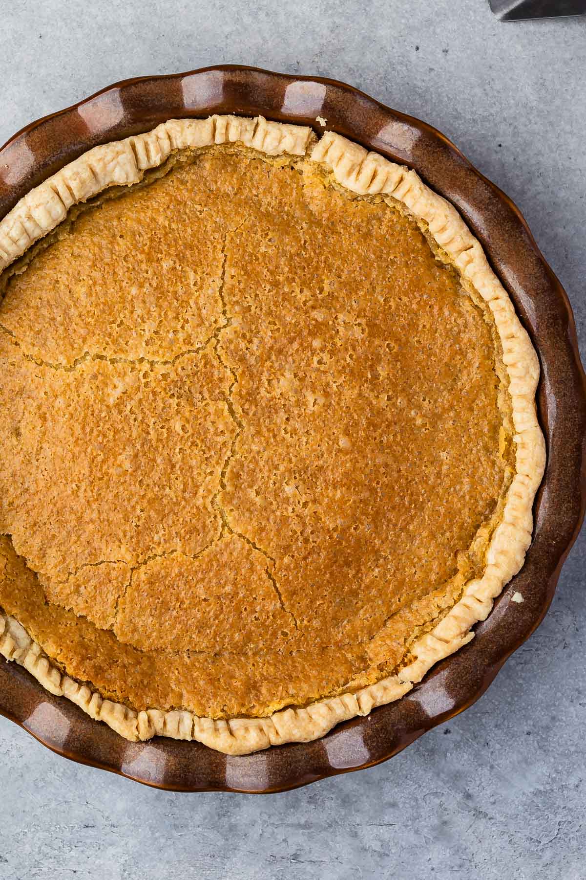 maple chess pie in a pie pan on a marble counter