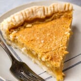 slice of maple chess pie on a tan plate next to a fork