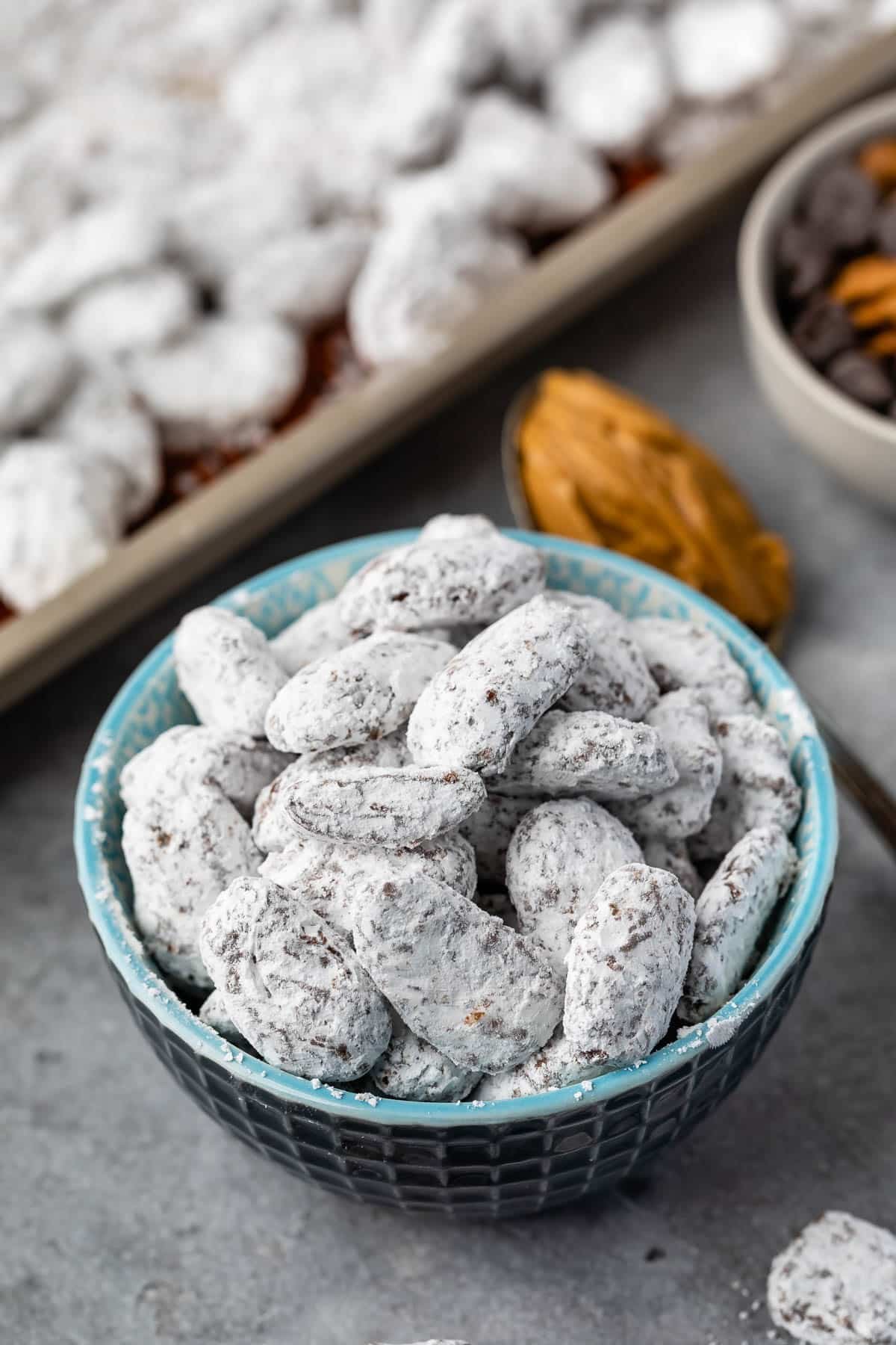 muddy buddies covered in powdered sugar in a blue bowl