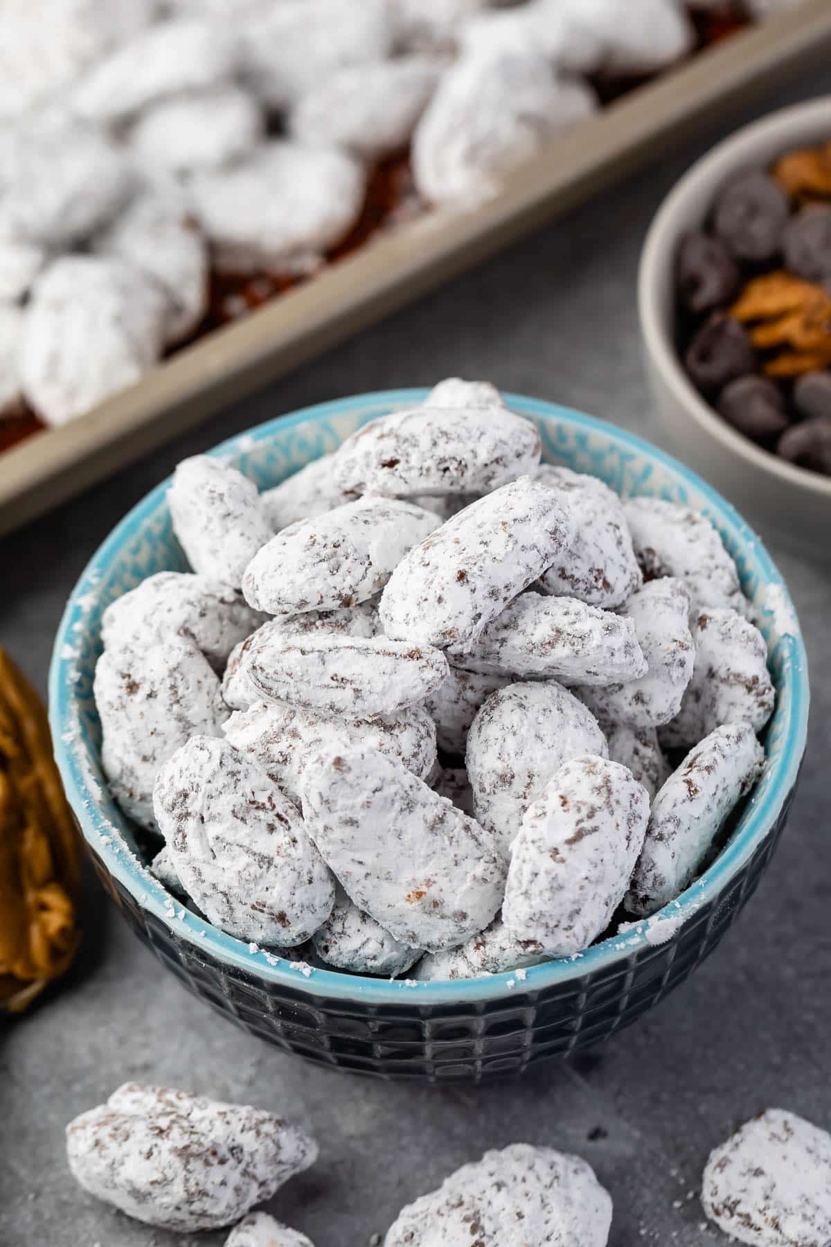 muddy buddies covered in powdered sugar in a blue bowl