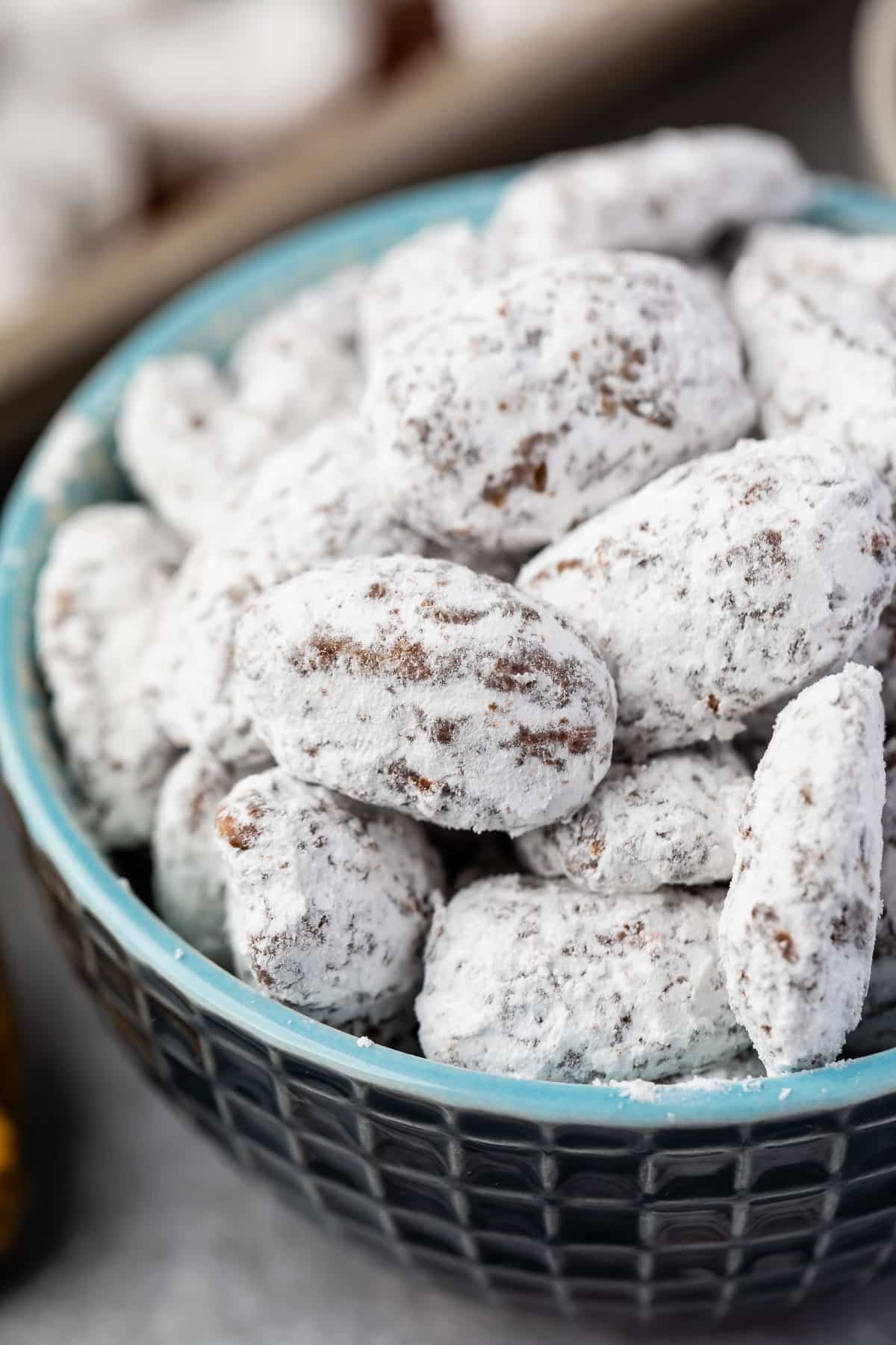 muddy buddies covered in powdered sugar in a blue bowl