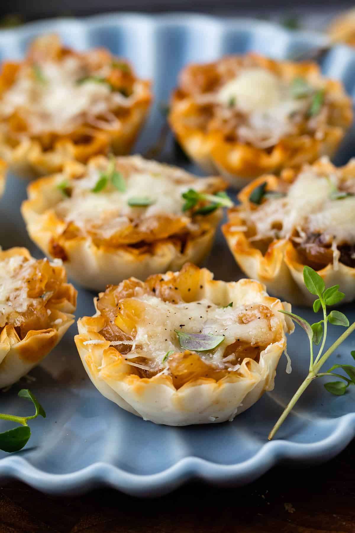 onion tarts on a blue plate with greens around them