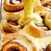 sweet rolls with frosting being poured out of a clear bowl onto the sweet rolls with words on the image